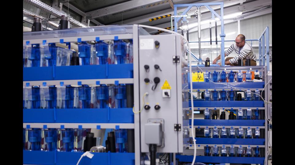 aquariums posés sur des racks pour être exposés à l'irradiation ; au second plan Nicolas Dubourg, responsable technique de l'installation plateforme d'irradiation MICADO © Francesco Acerbis/IRSN 